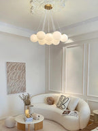 A curved white sofa and a textured wall print sit beneath this lit Clérachic cluster chandelier.