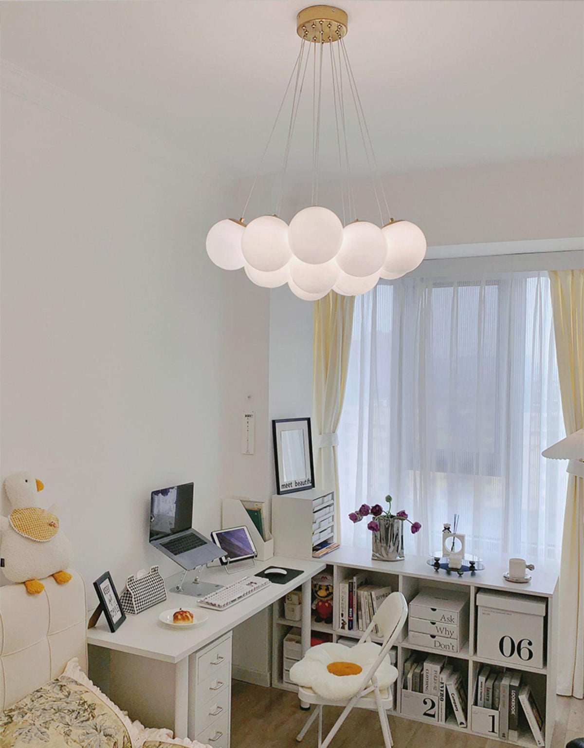 A desk and open shelving sit beneath this lit Clérachic cluster chandelier in a home study corner.