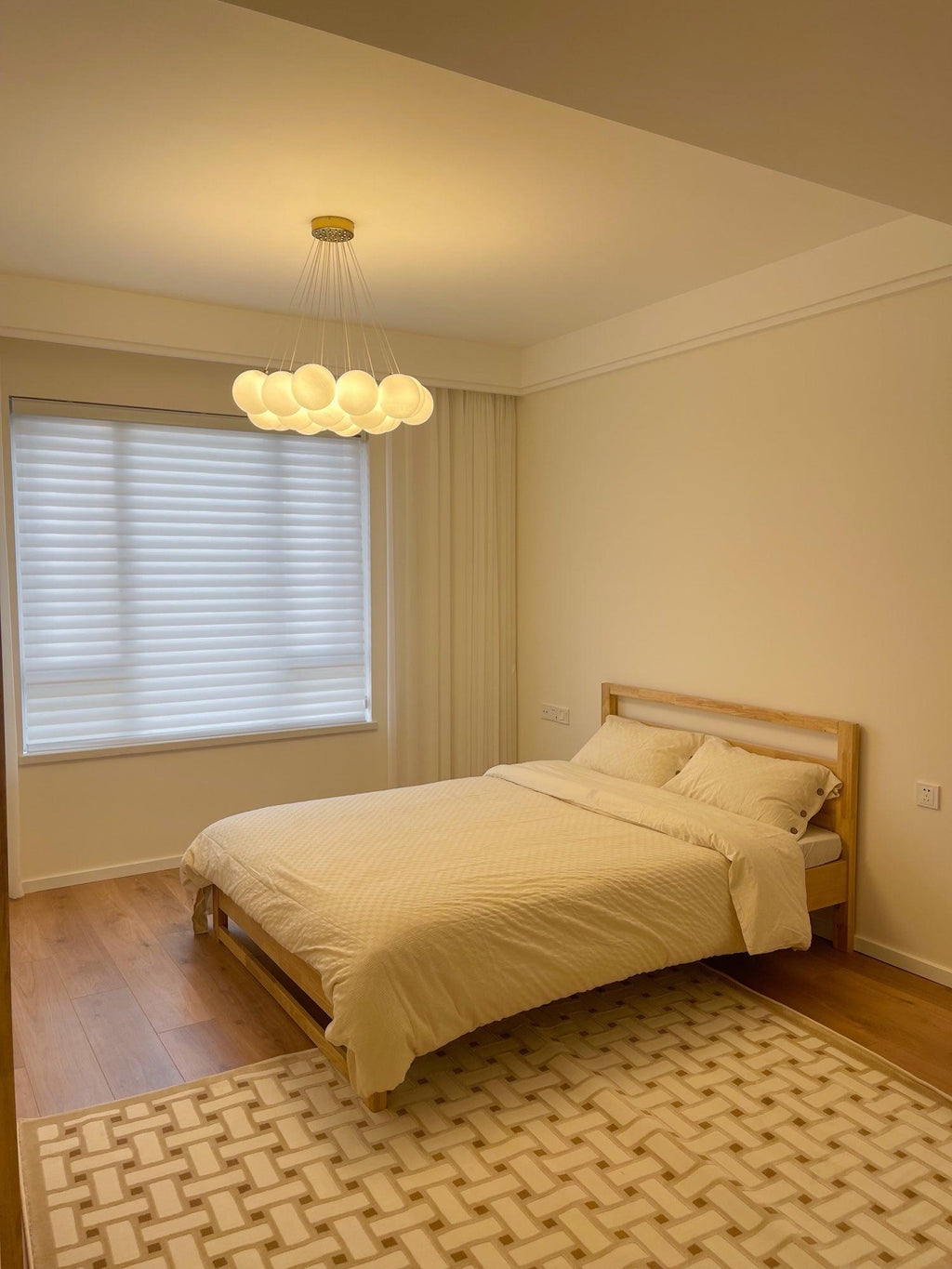 Mustard-toned bedding and a patterned rug sit beneath this lit Clérachic cluster chandelier.