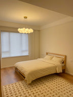 Mustard-toned bedding and a patterned rug sit beneath this lit Clérachic cluster chandelier.