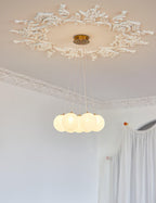Close view of the gold ceiling plate on this lit Clérachic cluster chandelier, set within an ornate plaster ceiling rose.
