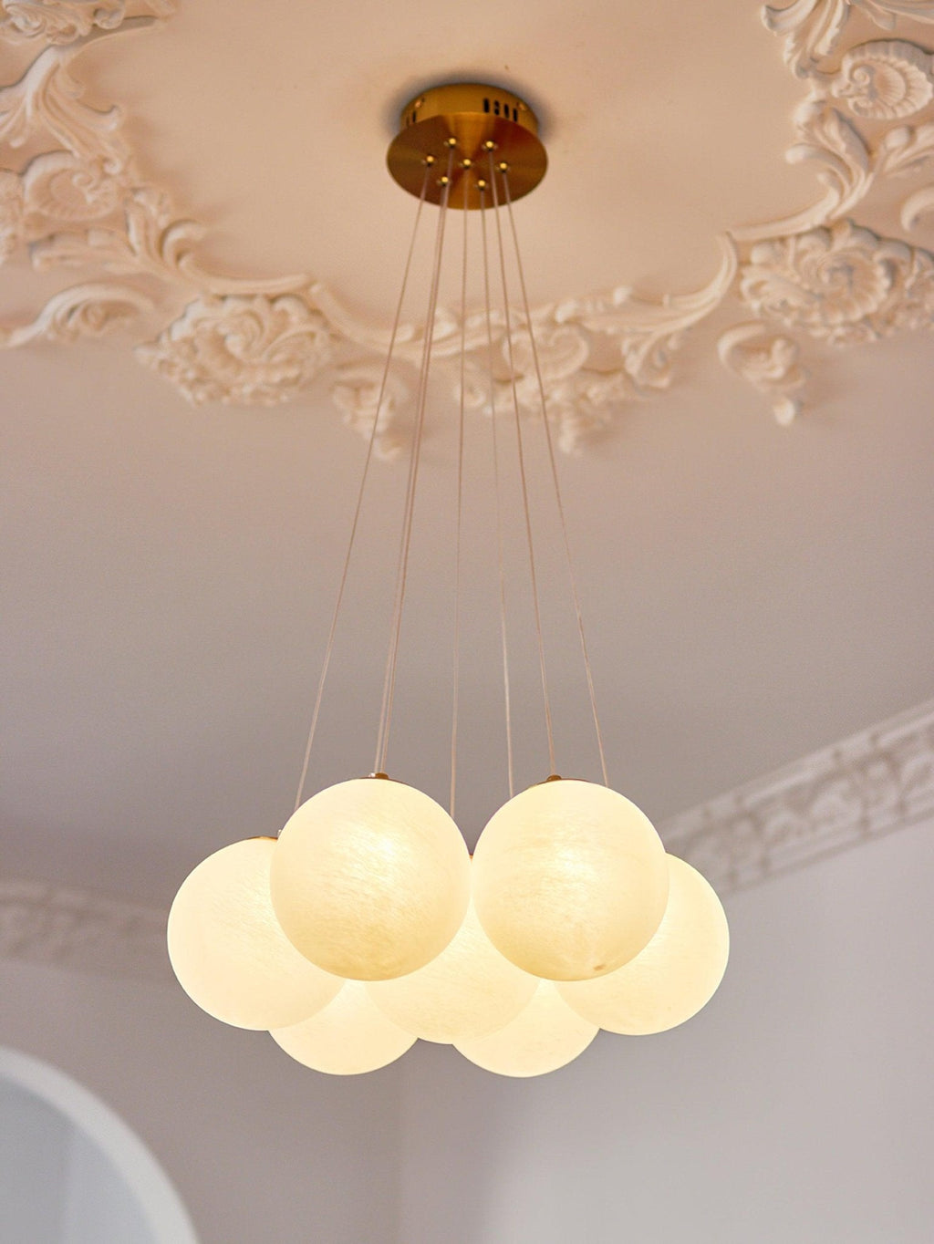 Another close view of the gold ceiling plate on this unlit Clérachic cluster chandelier against ornate plaster moulding.