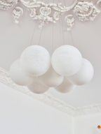 A close crop shows the frosted glass globes of this unlit Clérachic cluster chandelier gathered beneath ornate ceiling moulding.