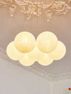 Lit and viewed from below, the frosted glass globes of this Clérachic cluster chandelier glow warmly beneath ornate moulding.