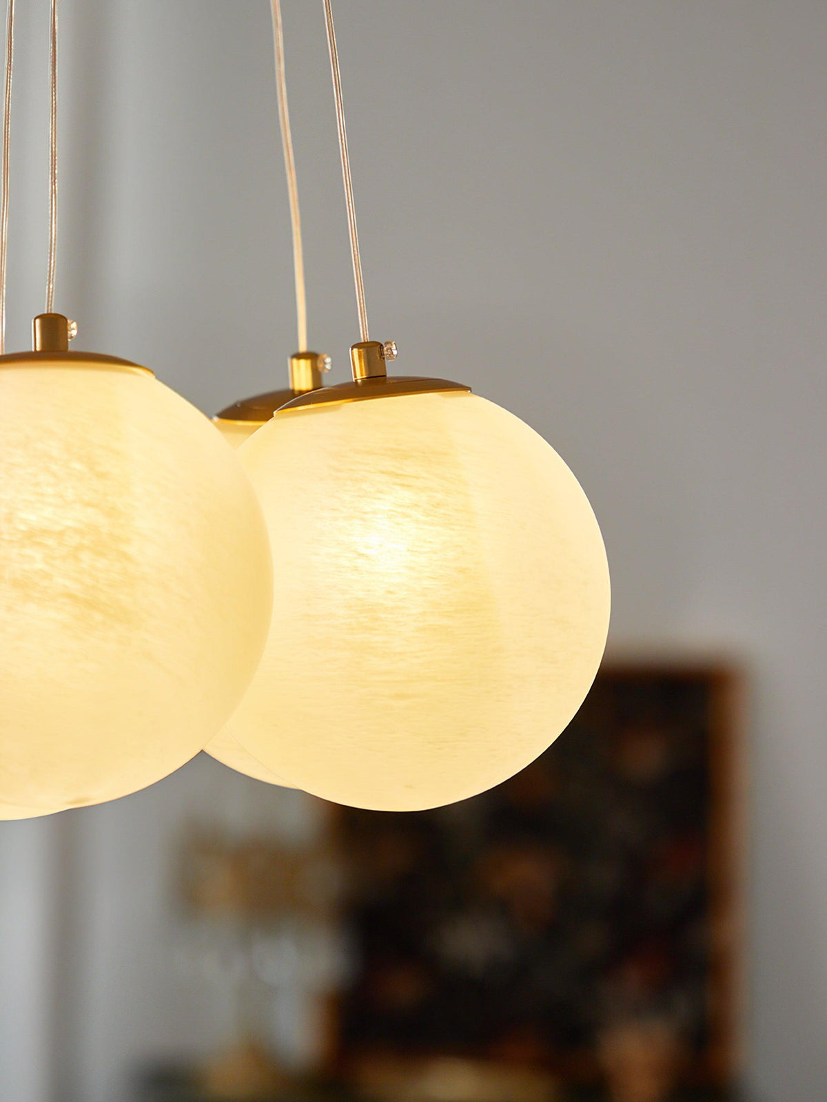 Extreme close-up of two lit globes on this Clérachic cluster chandelier, showing their swirled glass texture and gold caps.