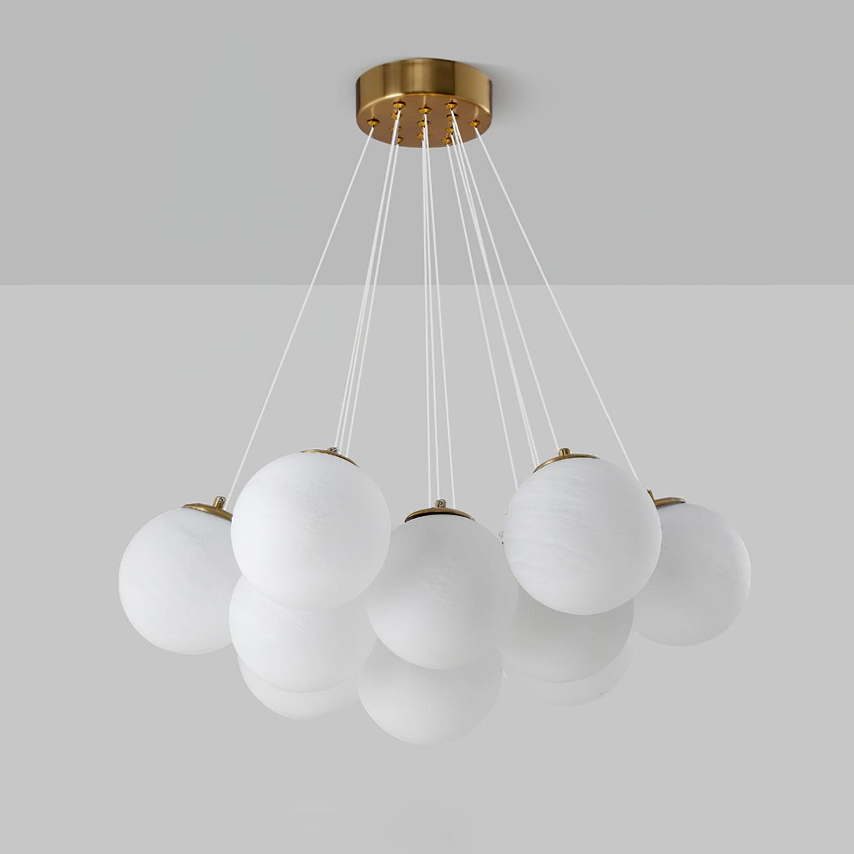 Against a two-tone grey backdrop, this Clérachic cluster chandelier shows gold caps fitted to each frosted glass globe.