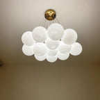 Seen close against the ceiling, this lit Clérachic cluster chandelier shows its gold mounting plate against a warm brown wall.