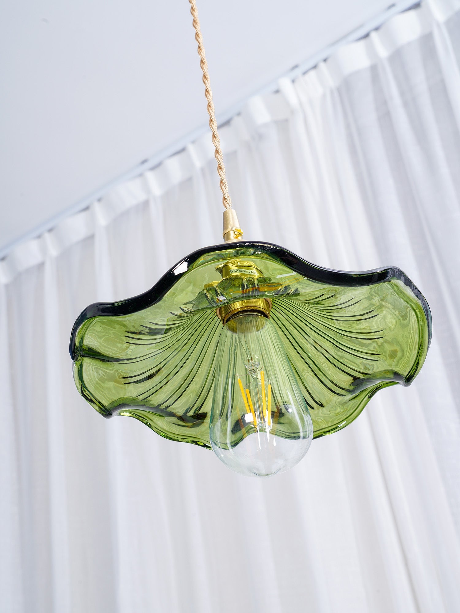 Clear glass hibiscus pendant light lit above a dining table