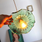 Glass hibiscus pendant light shown from below with warm glow