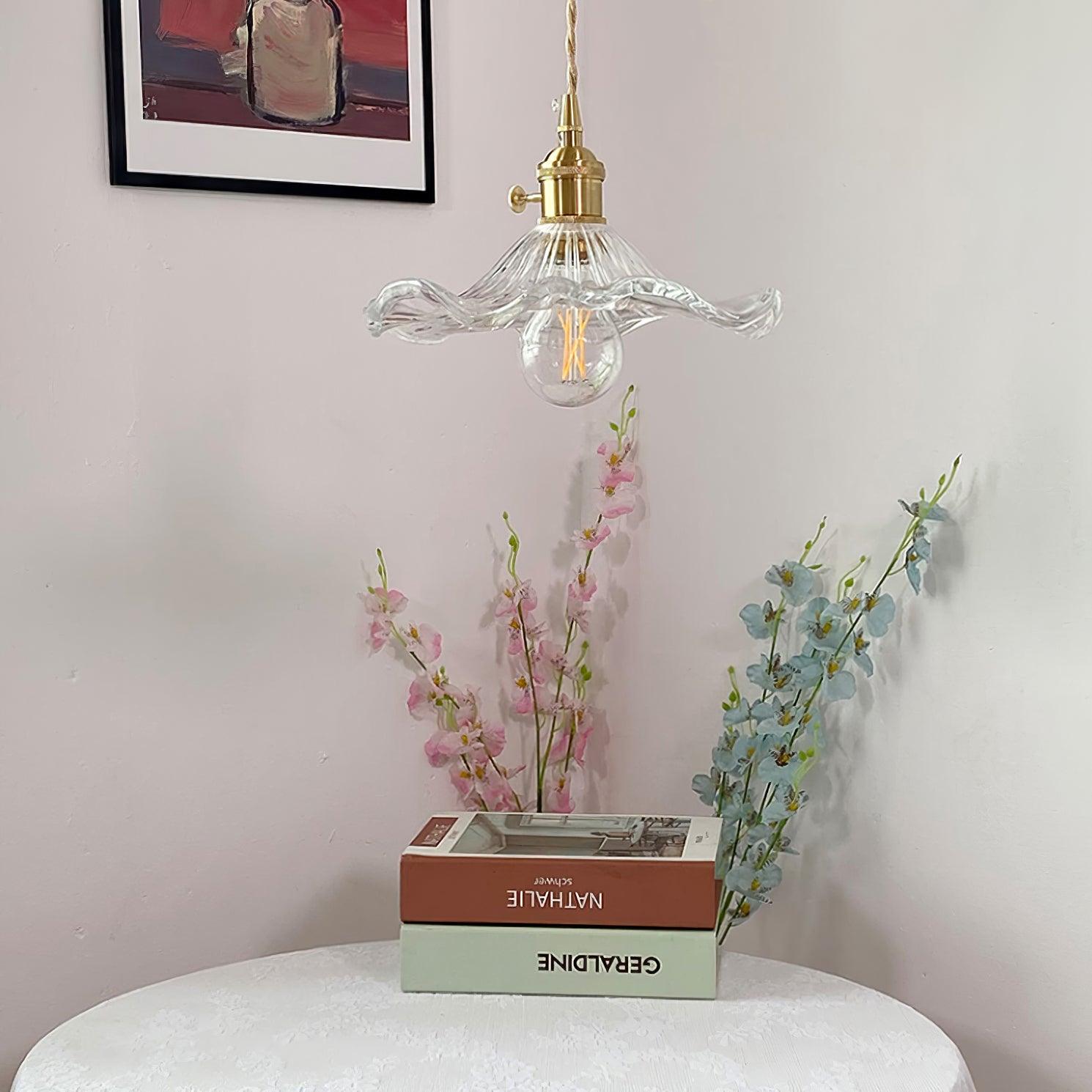 Hibiscus glass pendant light glowing beside a bedside corner