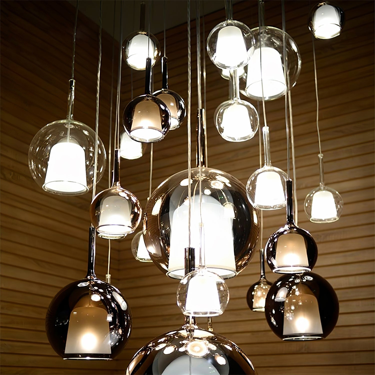 Glass globe pendant light shown lit over a wooden table