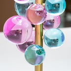 Glass sphere lamp casting kaleidoscopic light across a wall