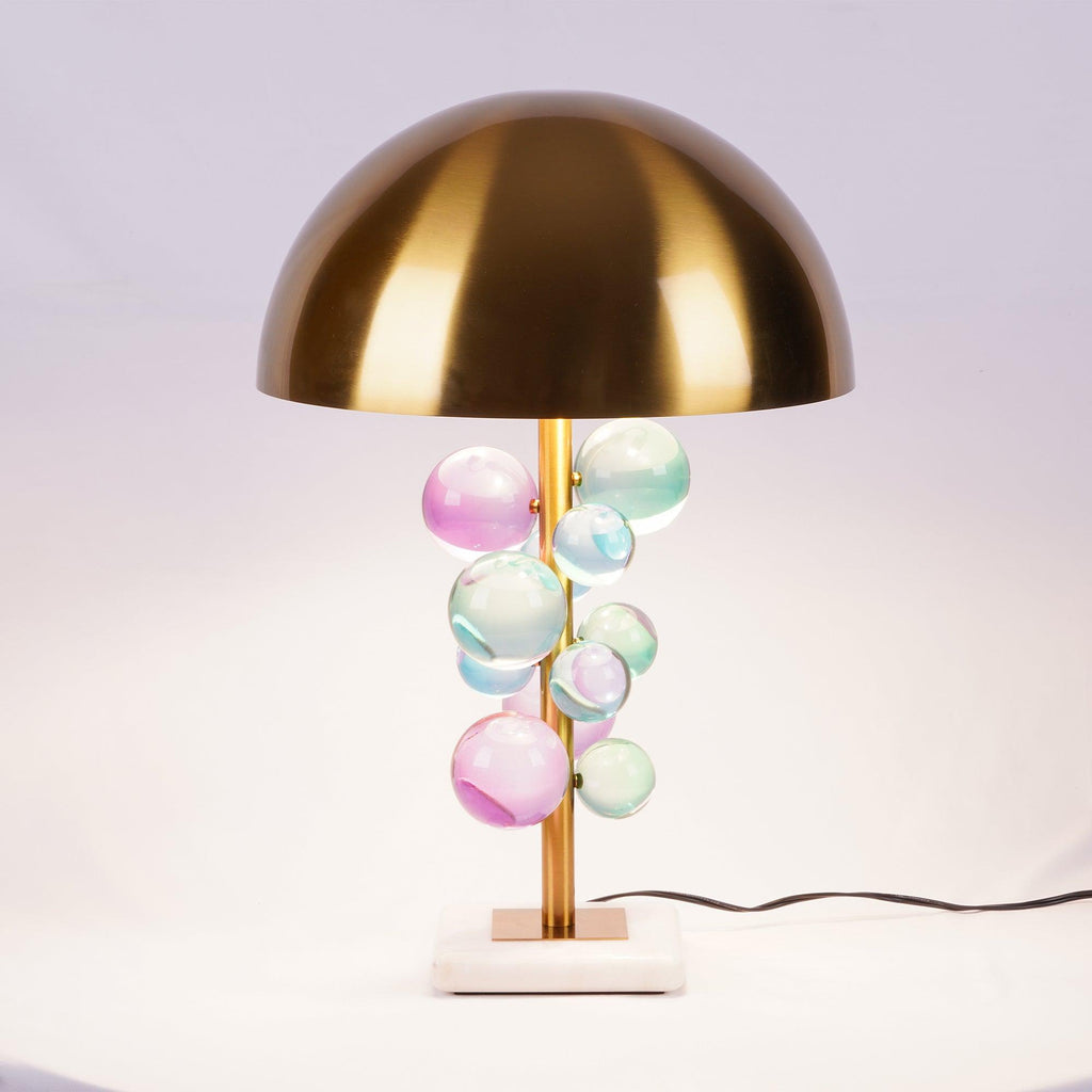 Glowing glass spheres on a gold stem above a white marble base