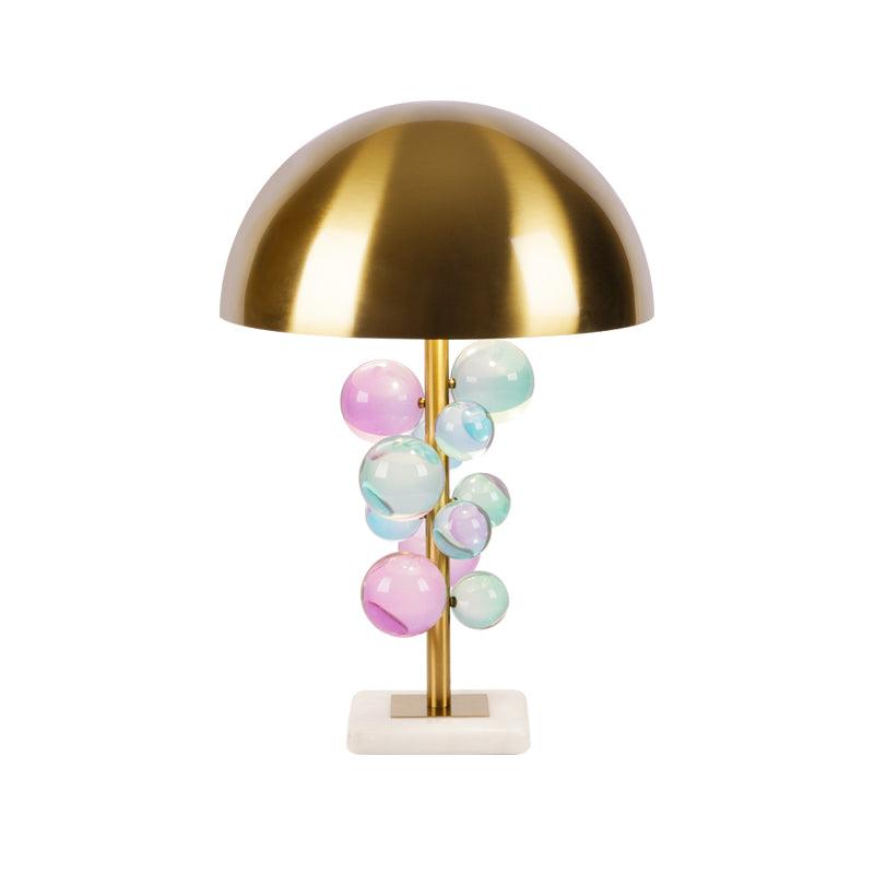 Cluster of clear glass spheres glowing warmly on the gold-stemmed lamp