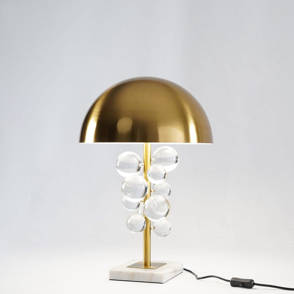 Glass spheres on a gold stem scattering warm light on a table