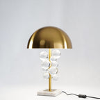 Glass spheres on a gold stem scattering warm light on a table