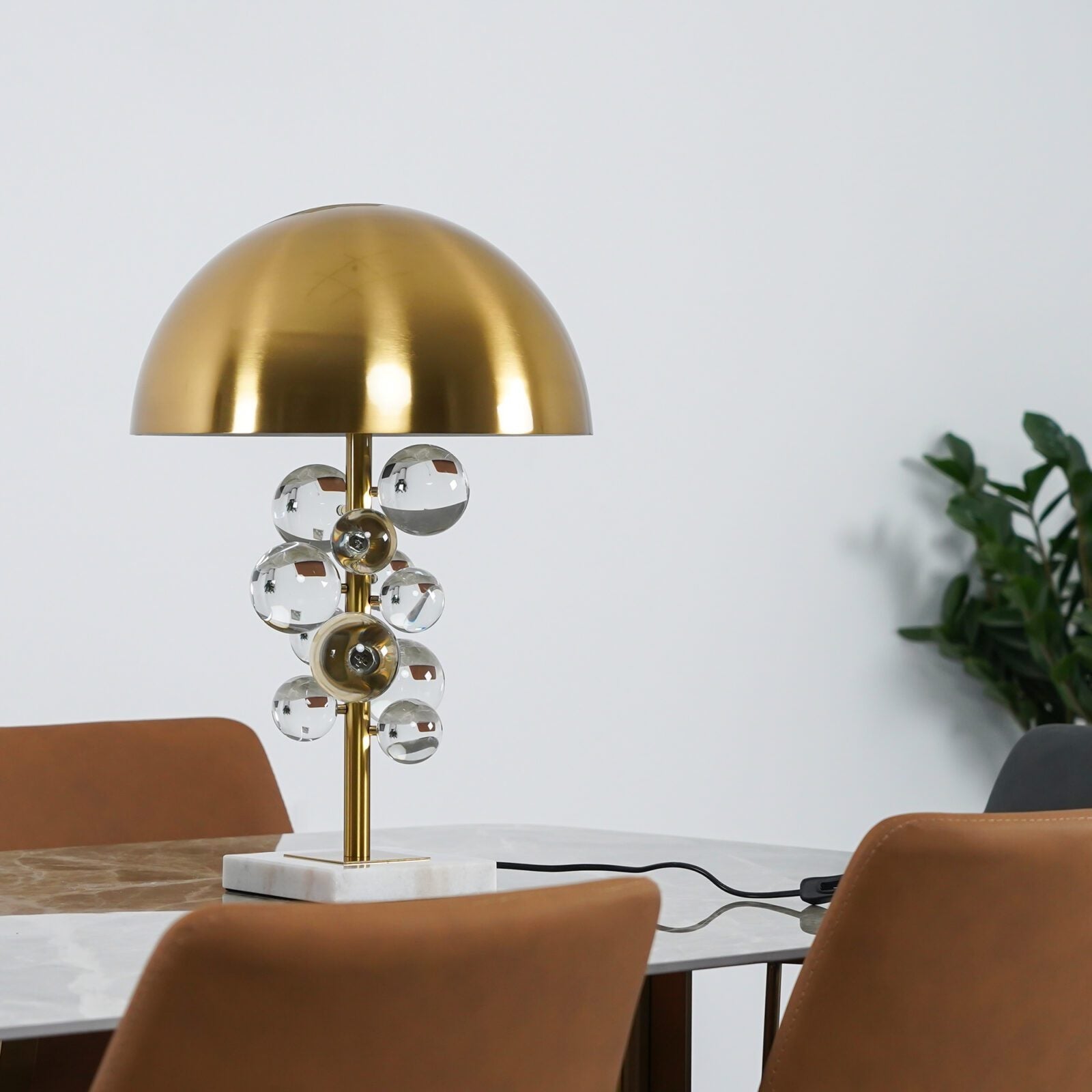 Globo table lamp with gold stem lit on a styled tabletop