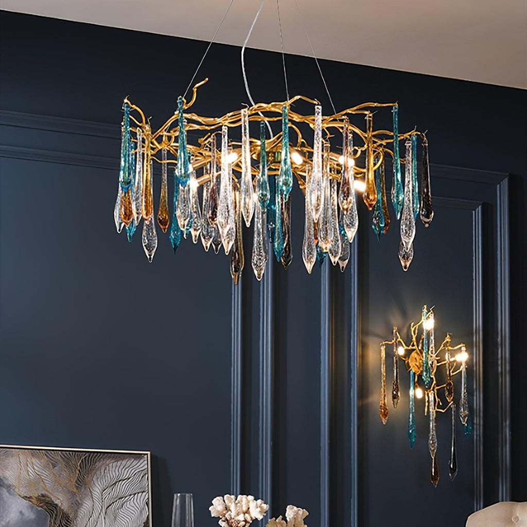 The chandelier lit above a navy panelled dining wall, with the matching wall sconce glowing to its right.