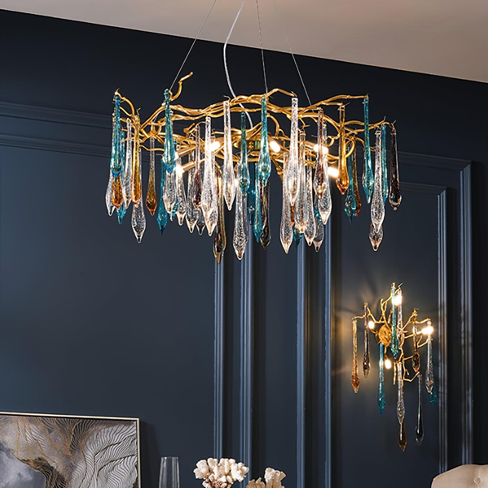 The chandelier lit above a navy panelled dining wall, with the matching wall sconce glowing to its right.