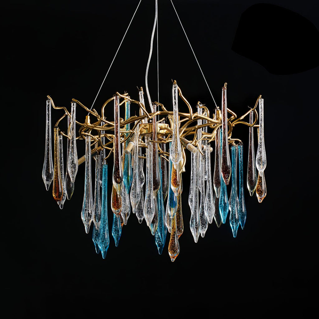 The chandelier lit against black, faceted clear, blue and amber teardrops hanging from a gold branch ring.