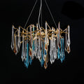 The chandelier lit against black, faceted clear, blue and amber teardrops hanging from a gold branch ring.