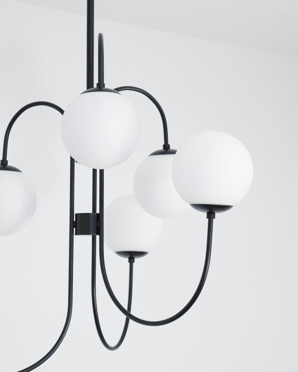Gooseneck chandelier arms curving to white glass globe shades