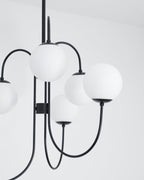 Gooseneck chandelier arms curving to white glass globe shades