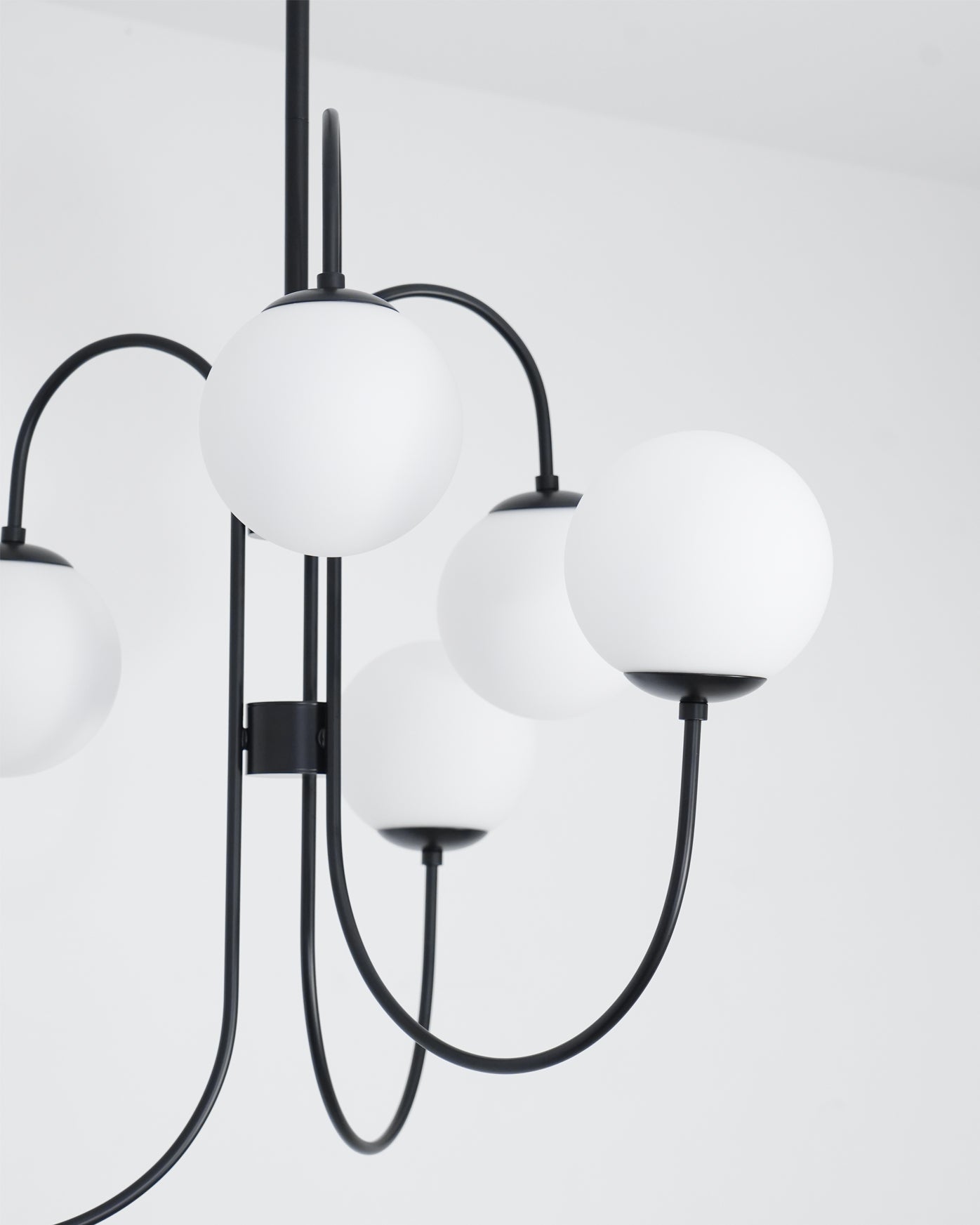 Gooseneck chandelier arms curving to white glass globe shades