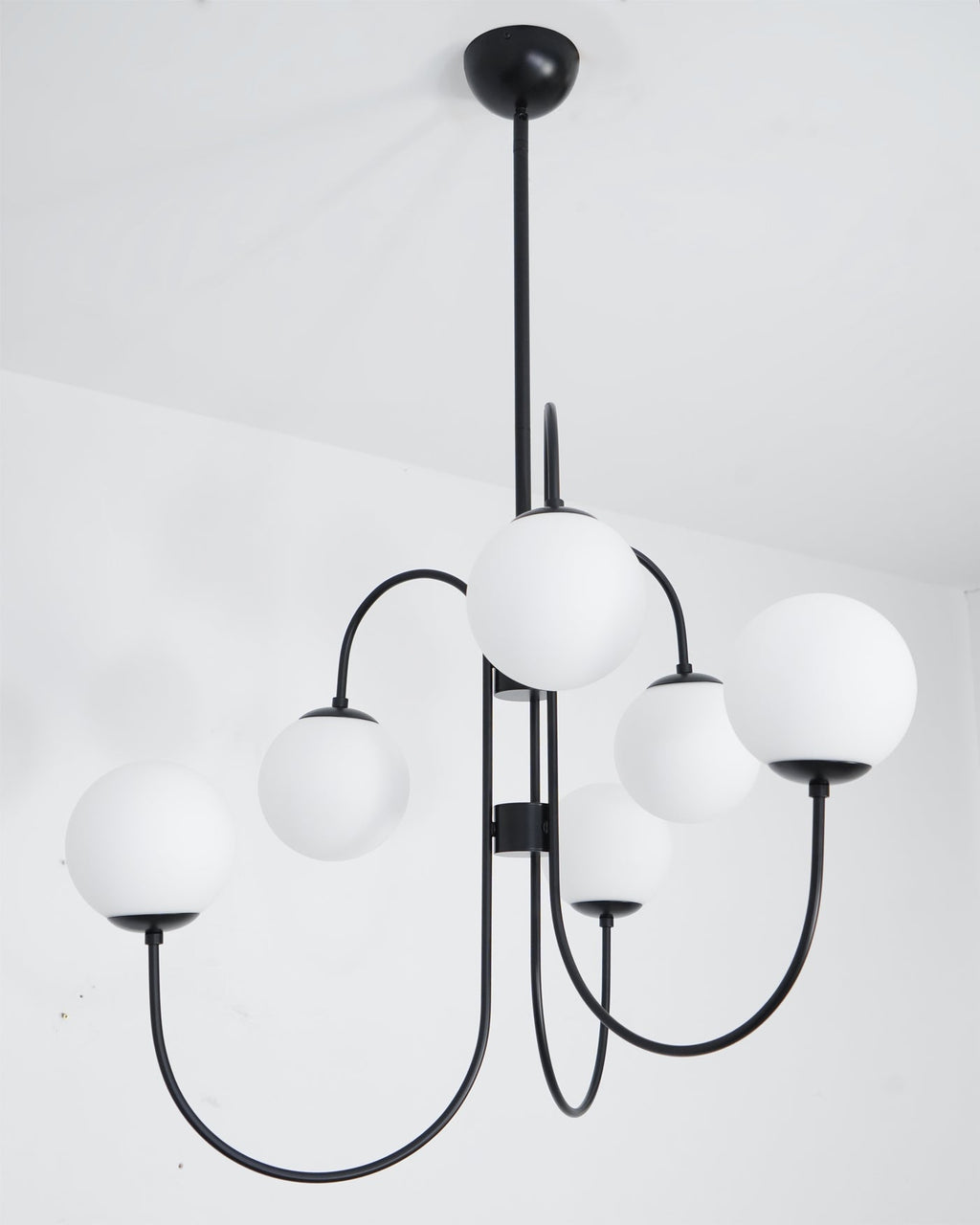 Gooseneck chandelier with iron arms and glowing white globes