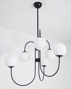 Gooseneck chandelier with iron arms and glowing white globes