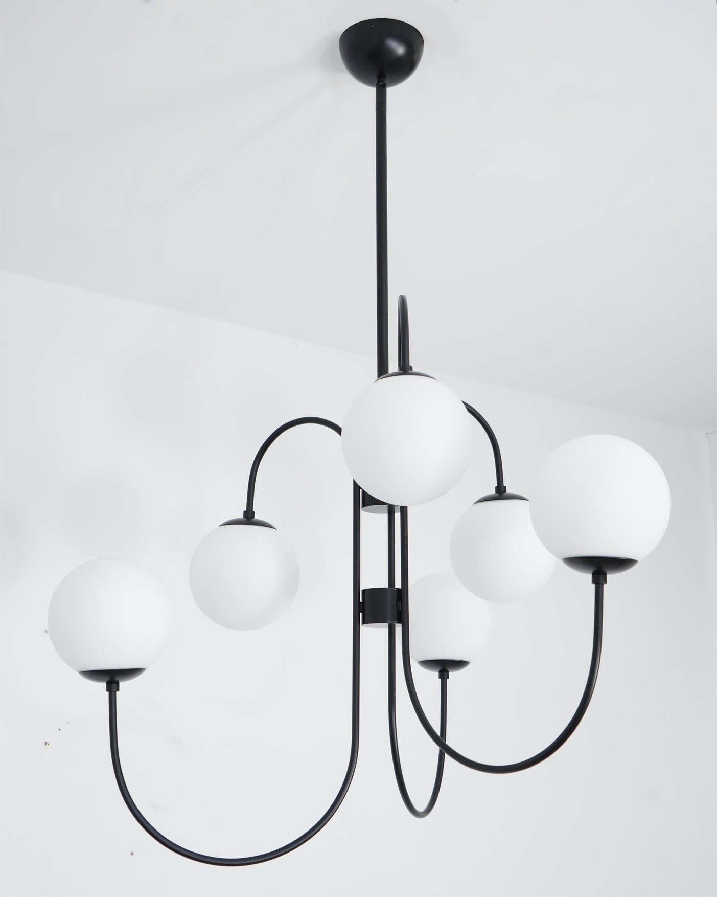 Gooseneck chandelier with iron arms and glowing white globes