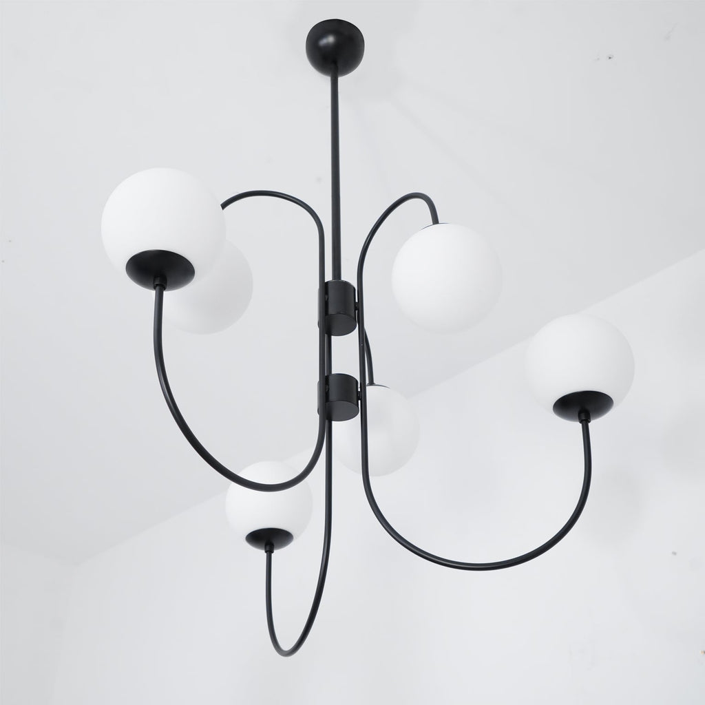 Gooseneck chandelier suspended over a warm dining setting