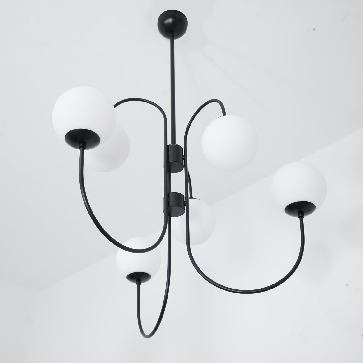 Gooseneck chandelier suspended over a warm dining setting