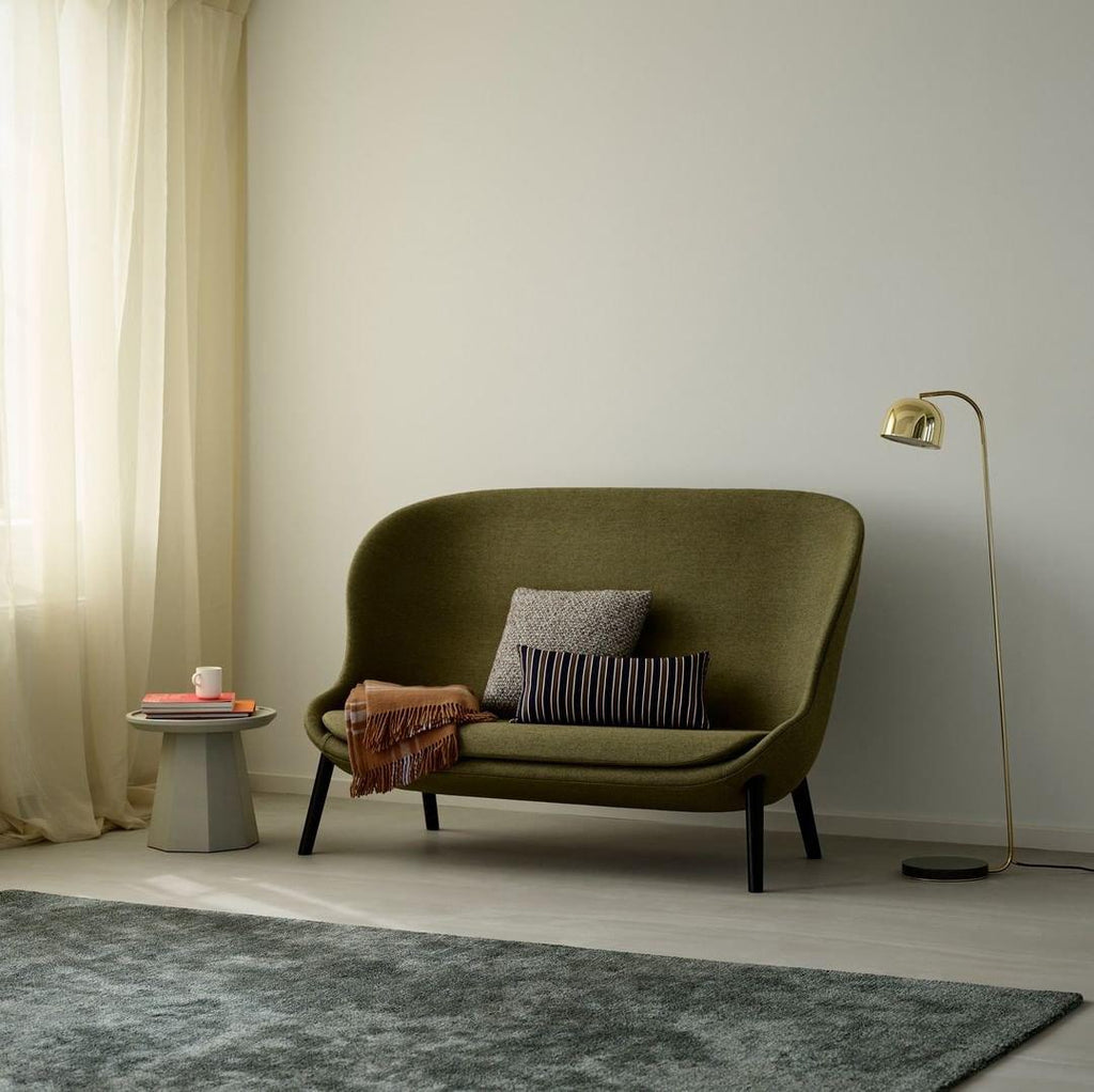 Gold dome-shade floor lamp from Clérachic in a bright living room beside an olive-green sofa and a round side table.
