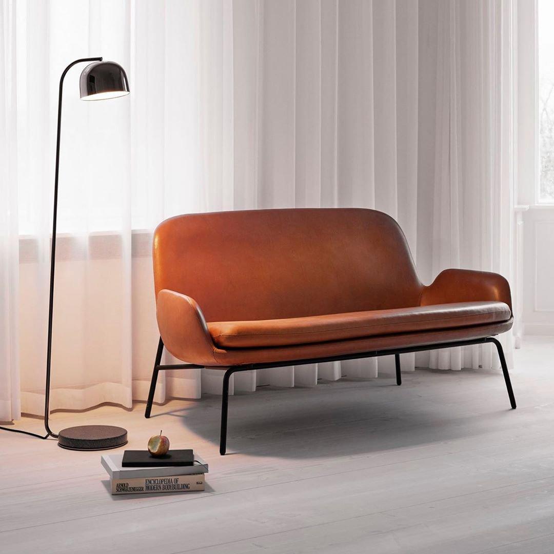 Black dome-shade floor lamp from Clérachic beside a burnt-orange sofa in a curtained studio living room.