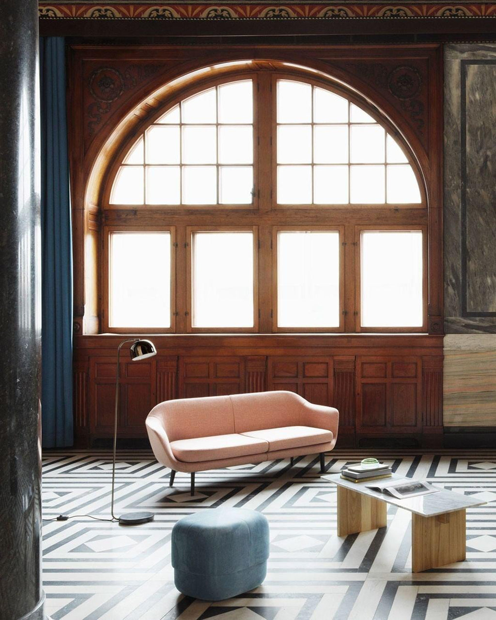Beside a pink sofa, this gold dome-shade Clérachic floor lamp stands before a tall arched window with wood panelling.