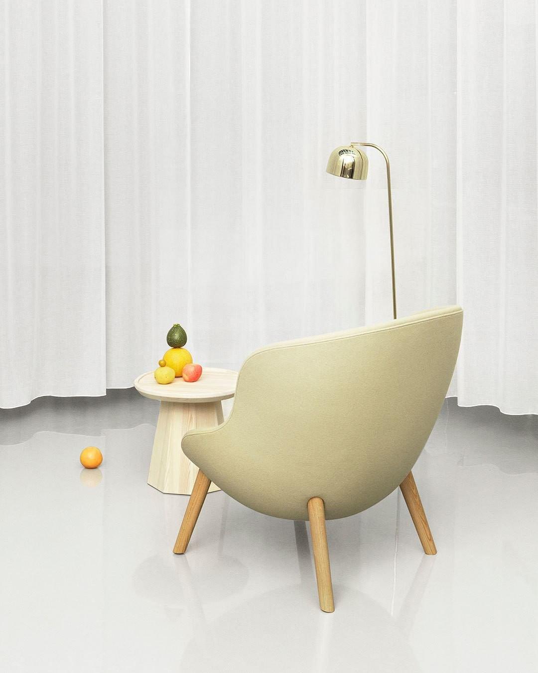 A round side table scattered with fruit sits by this gold dome-shade Clérachic floor lamp and a cream accent chair.