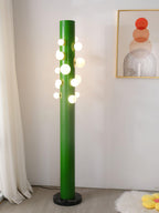 Photographed from a wider angle, the green Clérachic floor lamp still stands on a sheepskin rug near the framed print.