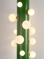 A close-up of the green Clérachic floor lamp shows its cluster of round frosted glass globes in varied sizes along the tube.