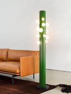 Next to a tan leather sofa and a dark cowhide rug, the green Clérachic floor lamp lights a warm living room corner.