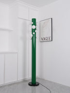 In the same white corner, the green Clérachic floor lamp appears unlit, its frosted globes plain against the fashion print.