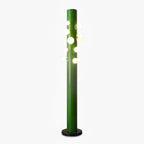 A green metal Clérachic floor lamp stands alone on white, its cluster of frosted glass globes glowing beside a round black marble base.