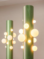 In dim evening light, two green Clérachic floor lamps glow together, their glass globes the main source of light in the room.