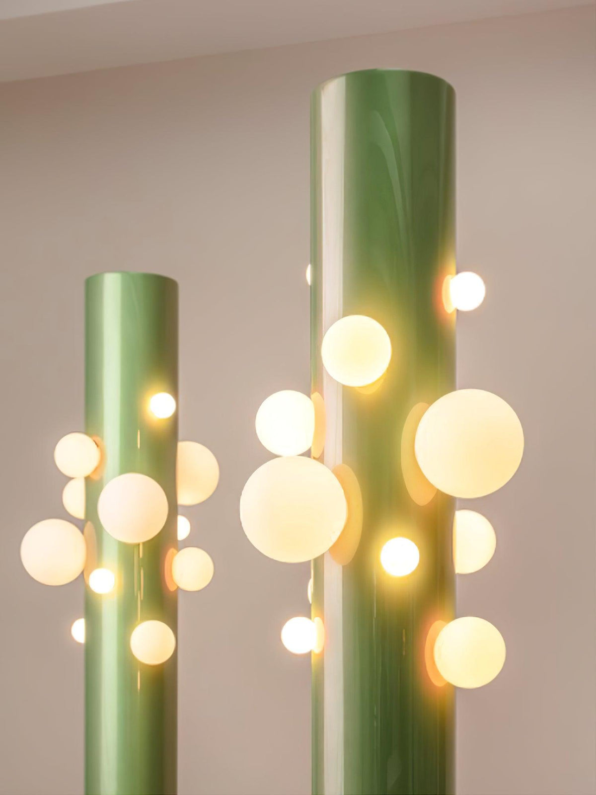 In dim evening light, two green Clérachic floor lamps glow together, their glass globes the main source of light in the room.