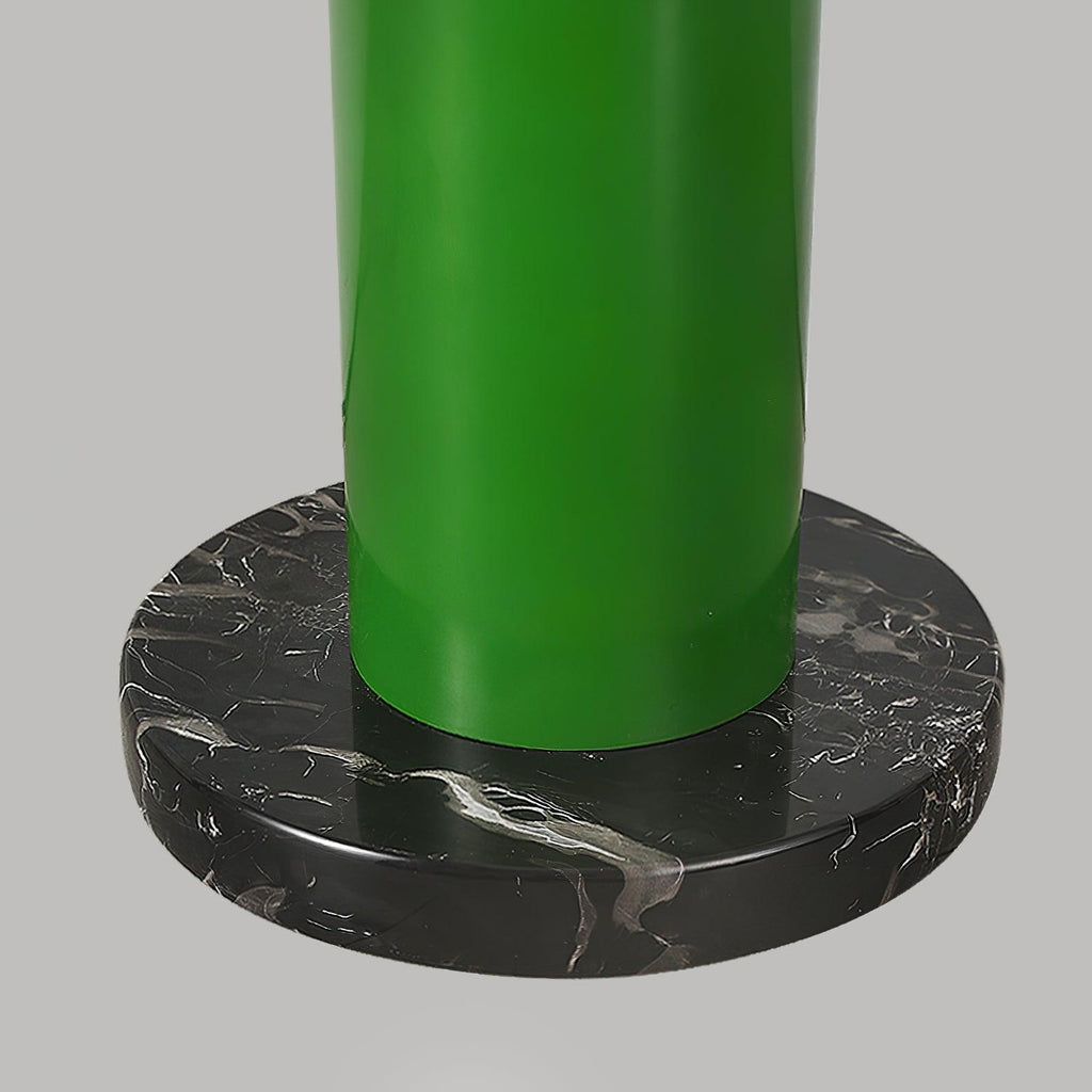 A close-up of the green Clérachic floor lamp's base shows the metal tube seated in a round black marble foot.