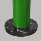 A close-up of the green Clérachic floor lamp's base shows the metal tube seated in a round black marble foot.