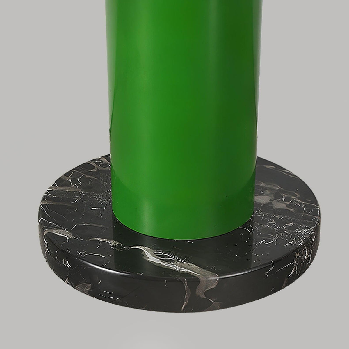 A close-up of the green Clérachic floor lamp's base shows the metal tube seated in a round black marble foot.