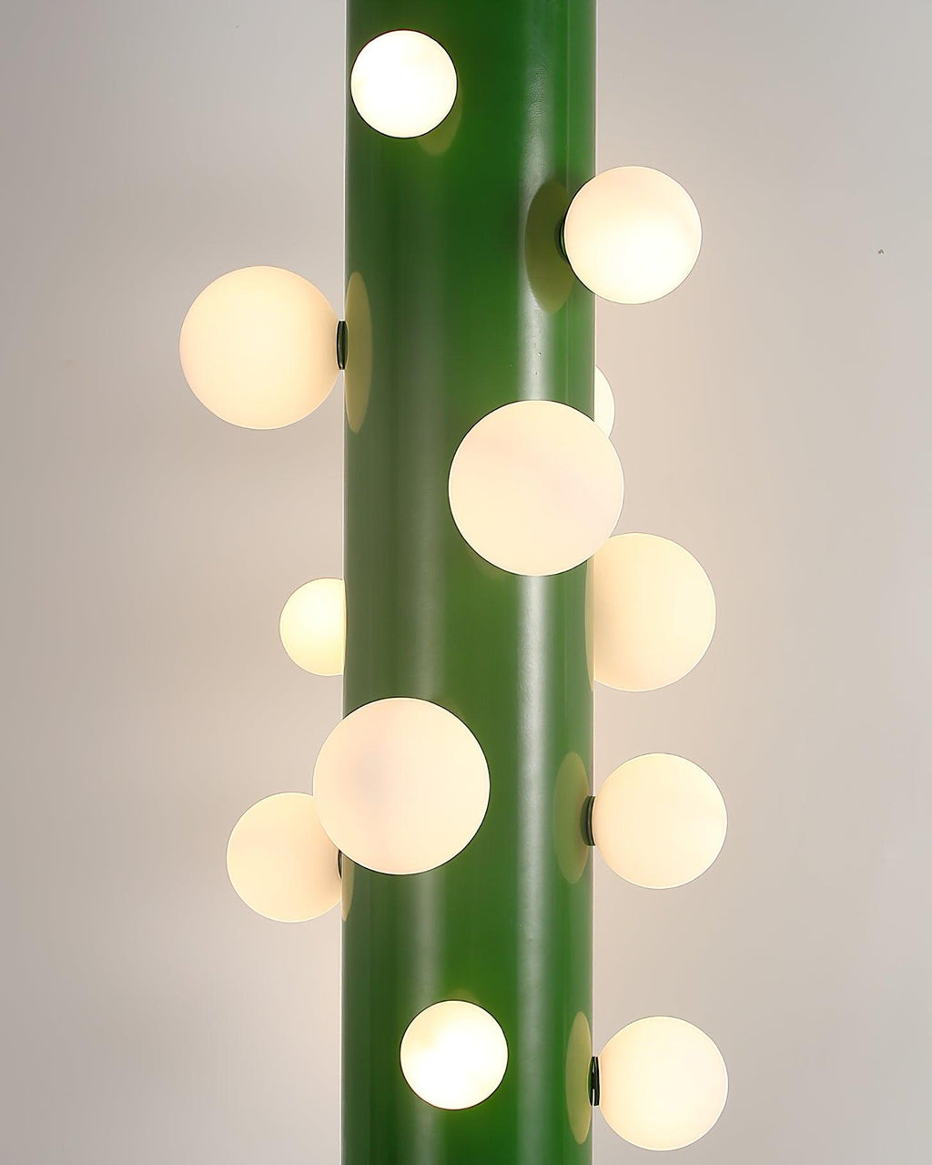 Another macro crop shows the green Clérachic floor lamp's frosted globes glowing warmly against its plain painted backdrop.