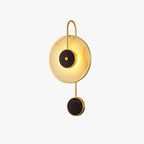 The fixture on white, a brass hook frame holding the alabaster disc above a small black disc.