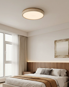Warm light from this Clérachic ceiling fixture falls over a bed with a wood-panelled headboard, beside a framed wall mirror.